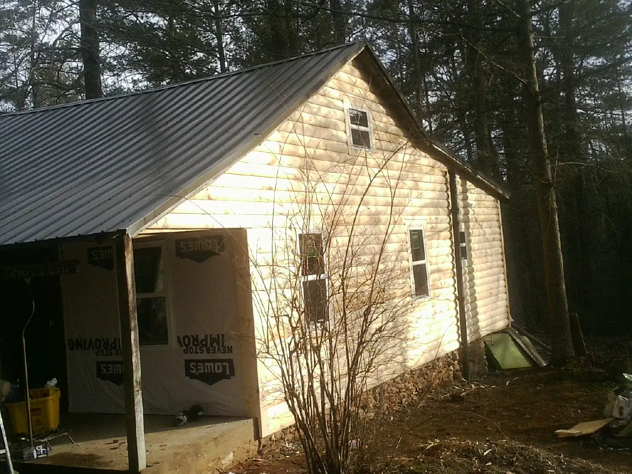 Log siding gable end under a dark metal roof edge in Republic